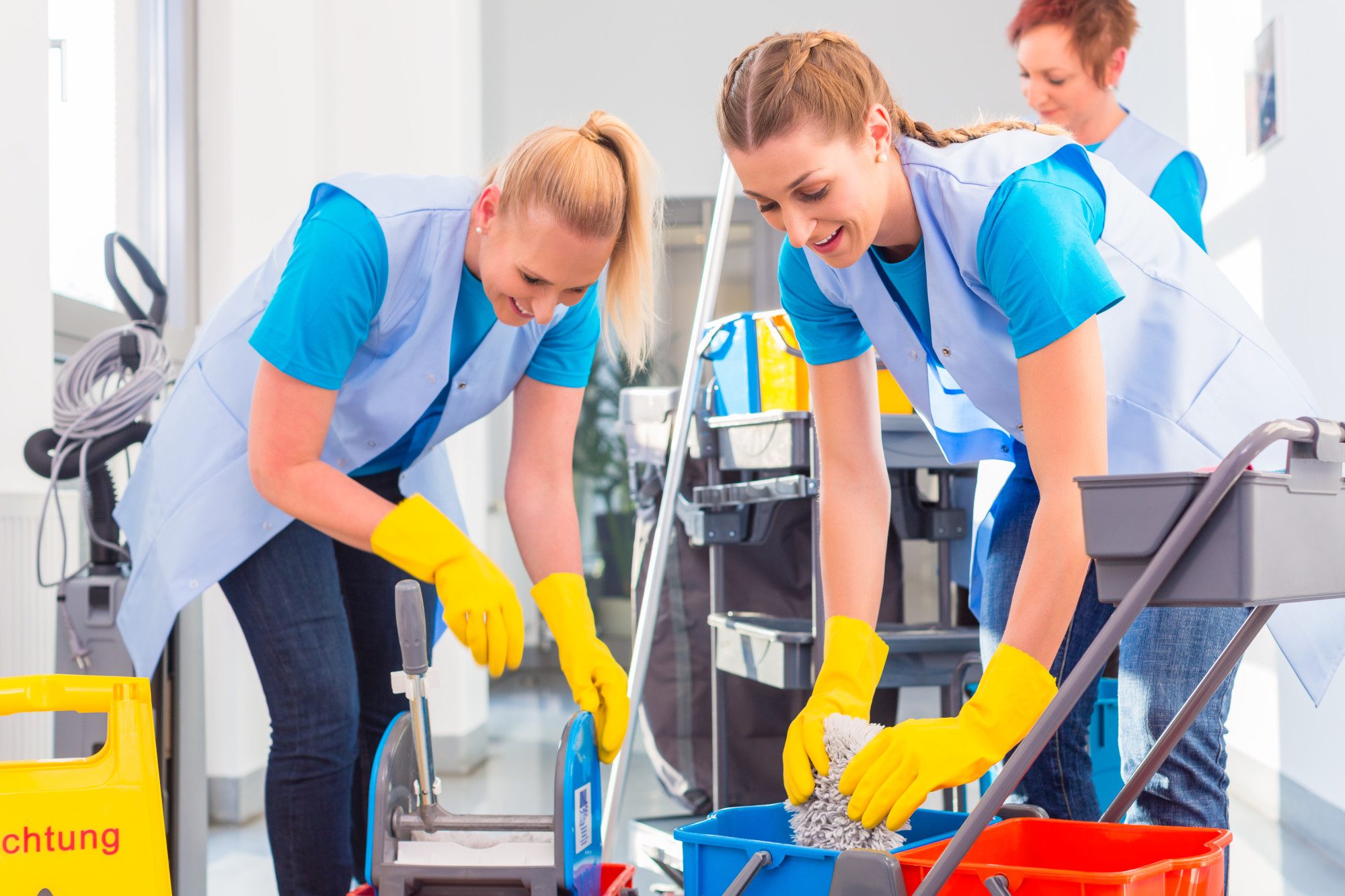 Commercial cleaners doing the job together, three women with trolley working